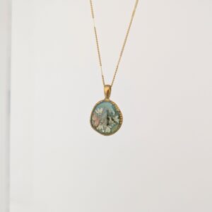 PXL_20261013_163151728PORTRAITORIGINAL - Blue Pendulum Jewelries Gold chain necklace with an oval turquoise pendant hanging against a light background.