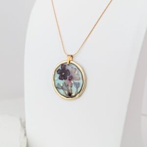 PXL_20261013_164710078PORTRAITORIGINAL - Blue Pendulum Jewelries Gold chain necklace with a teardrop-shaped pendant featuring a blue and purple floral design on a white background.