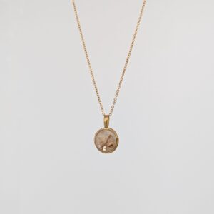 PXL_20261013_165243731PORTRAITORIGINAL - Blue Pendulum Jewelries Gold chain necklace with an oval pendant containing a dried leaf.