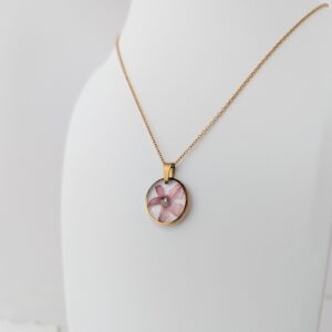 PXL_20261013_165733638 - Blue Pendulum Jewelries Gold chain necklace with a pink oval pendant resting on a white surface, close-up view.