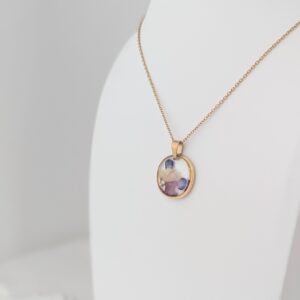 PXL_20261013_172111079PORTRAIT - Blue Pendulum Jewelries Gold chain necklace with an oval gemstone pendant on a white surface.