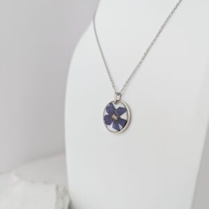 PXL_20261013_172749030 - Blue Pendulum Jewelries Silver chain necklace with an oval pendant showing a purple and white abstract design on a white surface.