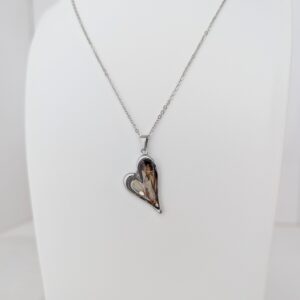 PXL_20261013_173555438 - Blue Pendulum Jewelries Silver necklace with a heart-shaped pendant hanging on a white display stand.