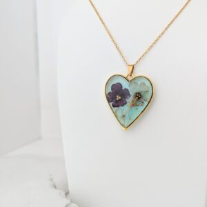 PXL_20261013_181533325 - Blue Pendulum Jewelries Gold chain necklace with a heart-shaped pendant featuring blue-green enamel and purple floral accents on a white background.