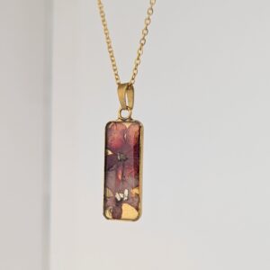 PXL_20261013_183651877PORTRAITORIGINAL - Blue Pendulum Jewelries Gold chain necklace with a rectangular pink marbled pendant hanging against a light background
